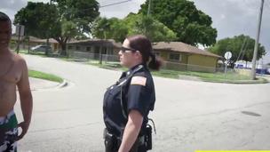 Two busty police officers in outdoor act with black guy